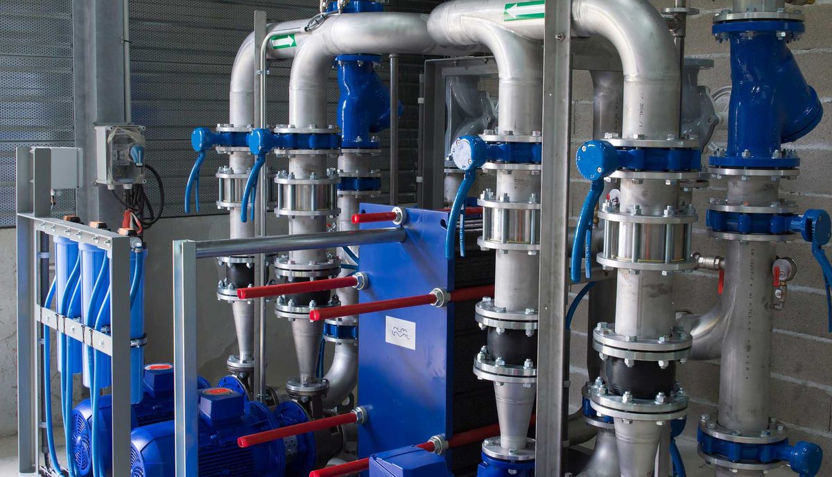 Process piping with blue valves and a plate heat exchanger in a plant room